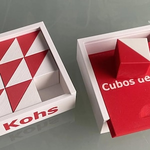 Pode incluir: Duas caixas quadradas brancas contendo blocos geométricos vermelhos e brancos. A caixa esquerda apresenta o texto Kohs e contém oito blocos com padrões triangulares. A caixa direita tem uma base vermelha com o texto Cubos de Kohs.