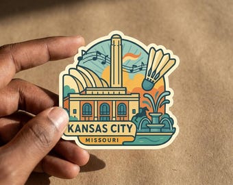 May include: A die-cut sticker featuring a stylized illustration of the Kansas City skyline, including the Liberty Memorial, a badminton shuttlecock, musical notes, and a fountain. The text reads KANSAS CITY MISSOURI in a bold, dark font.
