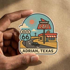 Puede incluir: Una pegatina troquelada con una ilustración gráfica del Midpoint Cafe en Adrian, Texas. El diseño incluye una señal de tráfico de la Ruta 66, un coche en una carretera sinuosa, un sol y un molino de viento bajo un cielo azul, con el texto ADRIAN, TEXAS.