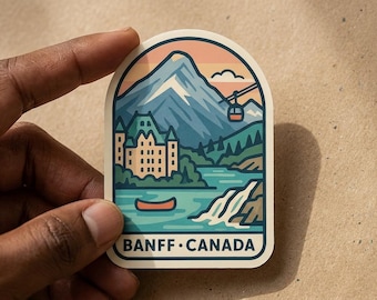 May include: A die-cut sticker featuring a graphic illustration of a mountain landscape in Banff, Canada. The design includes a large mountain, a castle-like building, a lake with a red canoe, a waterfall, and a cable car. The text BANFF CANADA is at the bottom.