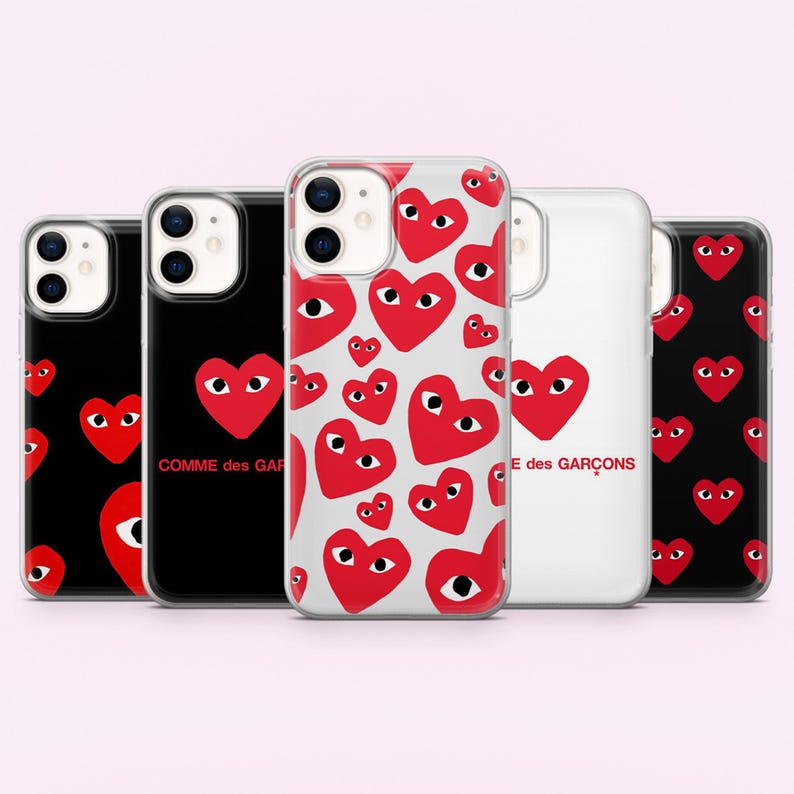 May include: Five phone cases with red heart graphics with eyes. The cases have a variety of designs, including a black case with a large red heart, a clear case with multiple red hearts, and a white case with a large red heart and text.