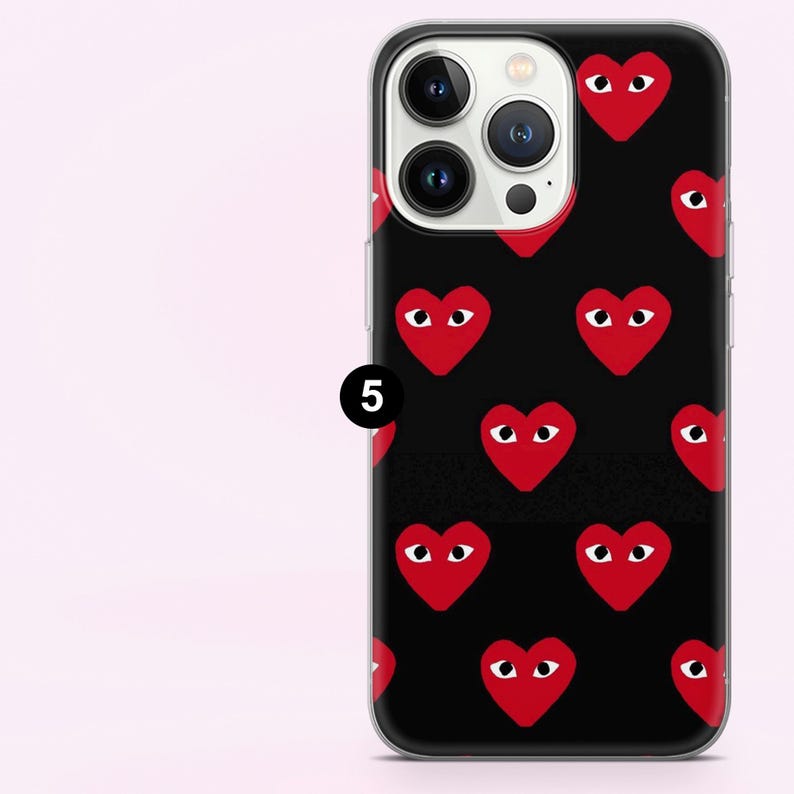 May include: Black phone case with a pattern of red hearts with white eyes. The case has a clear border and covers the back and sides of the phone. The phone's camera lenses are visible.