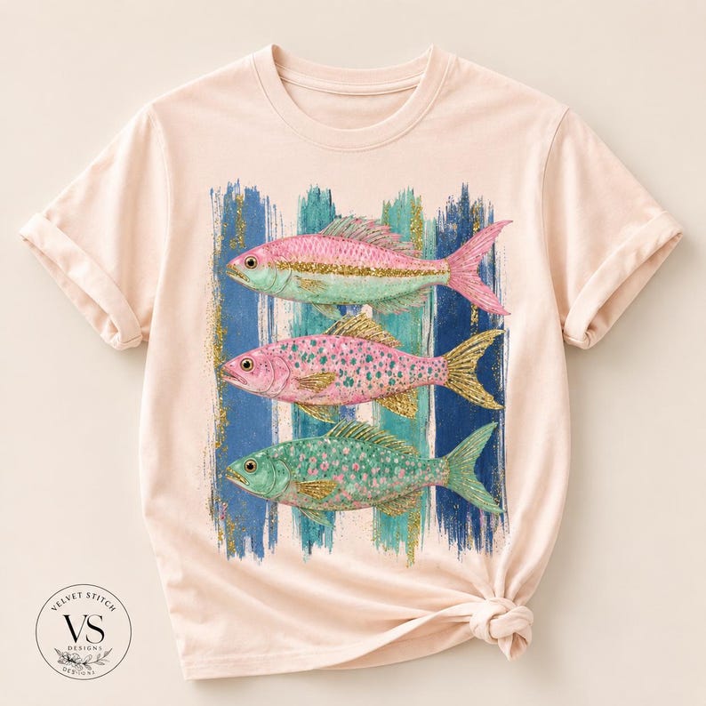 Pode incluir: Uma t-shirt de cor p&ecirc;ssego claro com uma estampa gr&aacute;fica de tr&ecirc;s peixes empilhados verticalmente. Os peixes s&atilde;o representados em tons de rosa, azul-petr&oacute;leo e detalhes em glitter dourado, sobre um fundo de pinceladas verticais azuis.