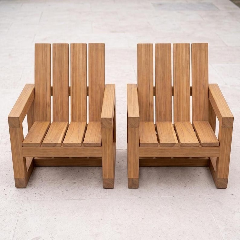 May include: Two matching armchairs constructed from light brown wood with a visible grain. Each chair features a high backrest composed of four vertical slats, a seat made of four horizontal slats, and two sturdy armrests supported by square legs.