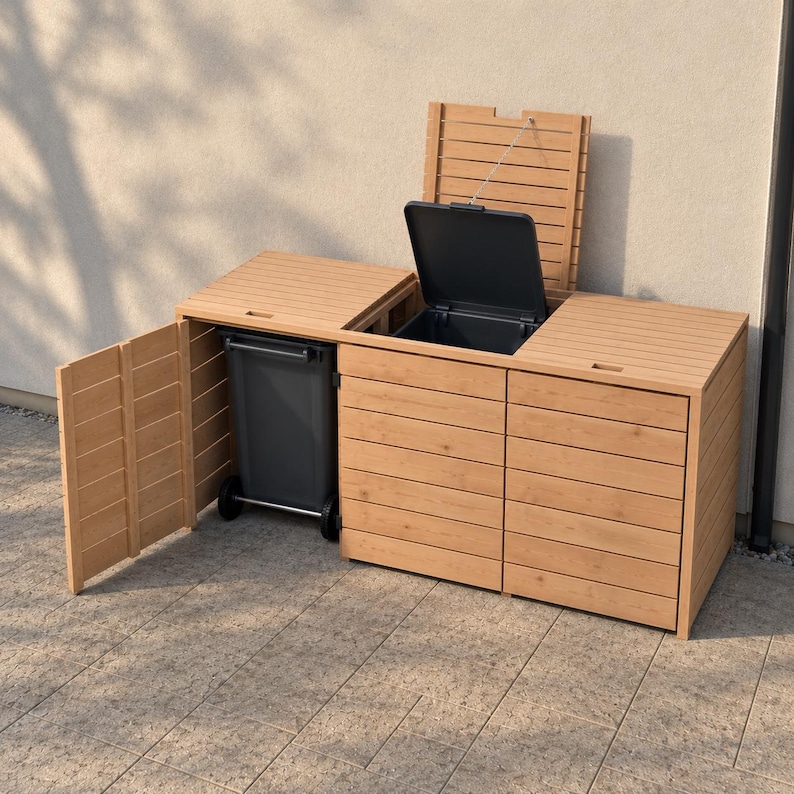 May include: A light brown wooden trash bin enclosure with three compartments. The left door is open, revealing a dark gray wheeled trash bin. The middle compartment lid is open, showing the interior, while the right lid remains closed.