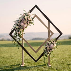 May include: A double diamond-shaped wooden frame arch featuring a dark brown outer frame and a light natural wood inner frame. The structure is decorated with two floral arrangements consisting of pink, white, and lavender roses with green foliage.