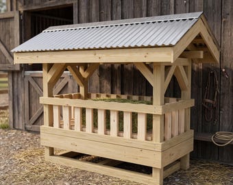 May include: A wooden hay feeder with a rectangular frame, vertical slats, and a corrugated metal roof. The structure is constructed from light-colored natural wood and features a sloped top design to protect the hay inside from the elements.