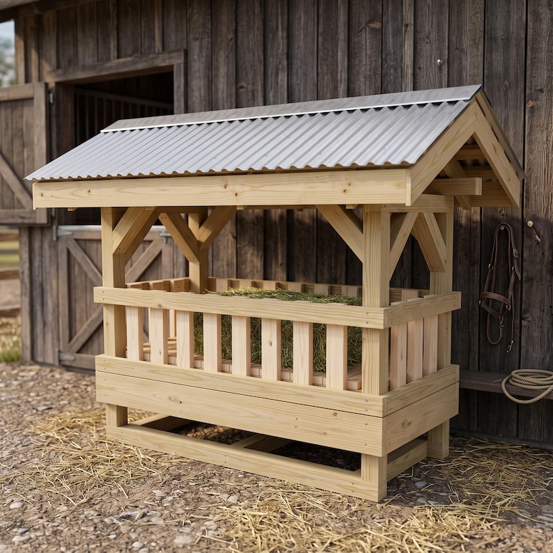 May include: A wooden hay feeder with a rectangular frame, vertical slats, and a corrugated metal roof. The structure is constructed from light-colored natural wood and features a sloped top design to protect the hay inside from the elements.