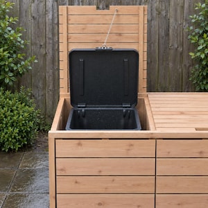 May include: A light brown wooden outdoor storage unit featuring horizontal slats and a hinged lid. The lid is held open by a metal chain, revealing a deep, black, rectangular plastic bin insert integrated into the top section of the structure.