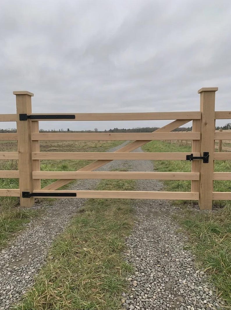 K&ouml;nnte beinhalten: Ein helles Holztor mit vier horizontalen Querlatten und einer diagonalen Verstrebung. Das Tor ist mit schwarzen Metallscharnieren an zwei quadratischen Holzpfosten befestigt und verf&uuml;gt &uuml;ber einen schwarzen Metallriegel auf der rechten Seite.