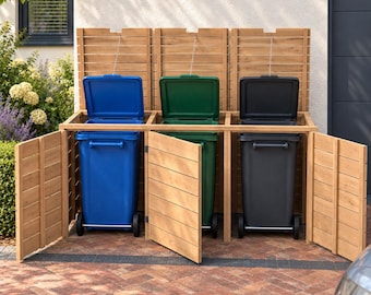 May include: A triple-bay wooden trash bin storage enclosure with horizontal slats and hinged doors. Inside are three upright wheeled bins in blue, green, and black, each with an open lid attached to the wooden structure by a metal chain.