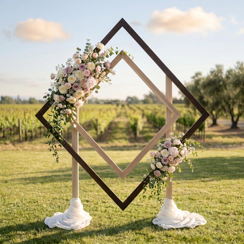 May include: A double diamond-shaped wooden frame structure featuring a dark brown outer frame and a lighter natural wood inner frame. The structure is adorned with two floral arrangements of white and pink roses and green foliage.