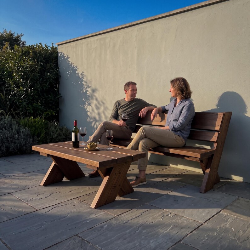 May include: A dark brown wooden outdoor bench and a matching low coffee table with a sturdy cross-leg design. The furniture is constructed from horizontal wooden planks and features a natural finish, positioned on a stone patio surface.