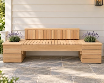 May include: A light-colored wooden bench featuring a slatted seat and a matching slatted backrest. The bench is flanked by two integrated square planters, each containing a small, bushy purple lavender plant with green foliage.
