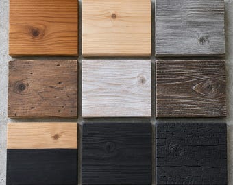 May include: A grid of nine rectangular wooden blocks featuring various finishes. The collection includes natural light wood, warm brown, weathered gray, dark brown, white-washed, solid black, charred black, and a two-toned block with natural and black.