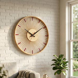 May include: A large, round wooden wall clock with a light wood finish and a sunburst design. The clock features black hands and red accents. It is mounted on a white brick wall in a living room setting.