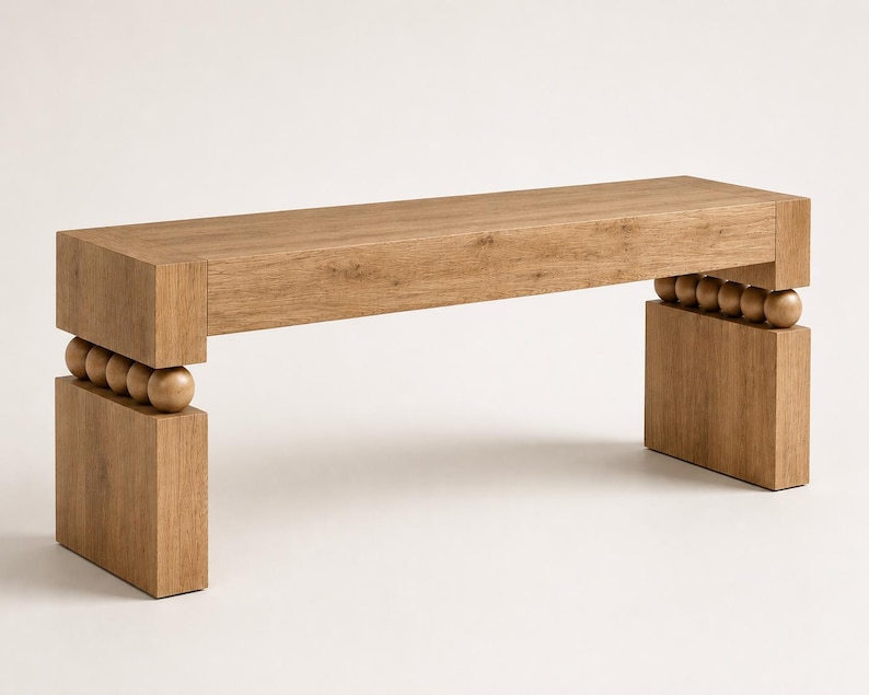 May include: A rectangular wooden bench with a light brown wood grain finish. The bench features a flat top surface supported by two thick, rectangular legs. Between the top and each leg are four spherical wooden beads arranged in a horizontal row.