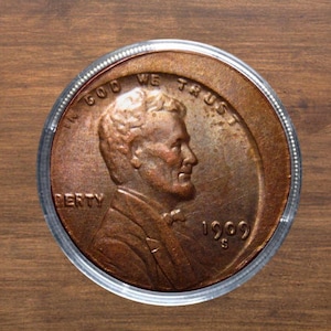 May include: A copper-colored 1909 S Lincoln cent coin, encased in a clear protective holder. The coin features a profile of Abraham Lincoln and the inscriptions "IN GOD WE TRUST" and "LIBERTY". The year "1909" is visible.