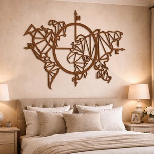 Può includere: Un'opera d'arte da parete in legno marrone raffigurante una mappa del mondo con un design a bussola. La mappa è in stile geometrico, con i continenti delineati. La rosa dei venti è centrata, con 'N' ed 'E' chiaramente indicate. L'opera è sopra un letto.