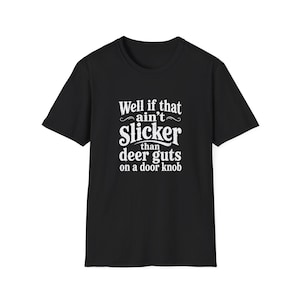 Könnte beinhalten: Ein schwarzes kurzärmeliges T-Shirt mit weißem Text auf der Brust, der lautet: Well if that ain't Slicker than deer guts on a door knob. Das Kleidungsstück hat einen Rundhalsausschnitt und eine Standardpassform, wobei die Grafik fett gedruckt ist.