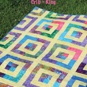 Op de afbeelding: Een kleurrijke quilt met een geometrisch patroon, met vierkanten in vierkanten in tinten geel, blauw, paars, groen en roze. De tekst "Cha Cha Cha" en "2 1/2" Strip Pattern" zijn zichtbaar. De quilt is ontworpen voor wieg- en kingsize maten.