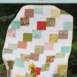 May include: A quilt pattern called "Ribbon Waltz" by Harding Hill Designs. The pattern makes five sizes, from crib to king, using 5-inch squares. The quilt is made with a variety of colorful fabrics, including red, green, yellow, and blue.