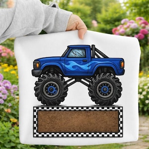 May include: White pillow with a blue monster truck design. The truck has large black tires, blue flames, and a brown rectangular space with a black and white checkered border.