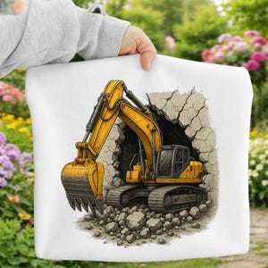 May include: White tote bag with a vibrant illustration of a yellow excavator, complete with black detailing, breaking through a concrete wall. The design includes rocks and a dark opening. The bag is held by a person.