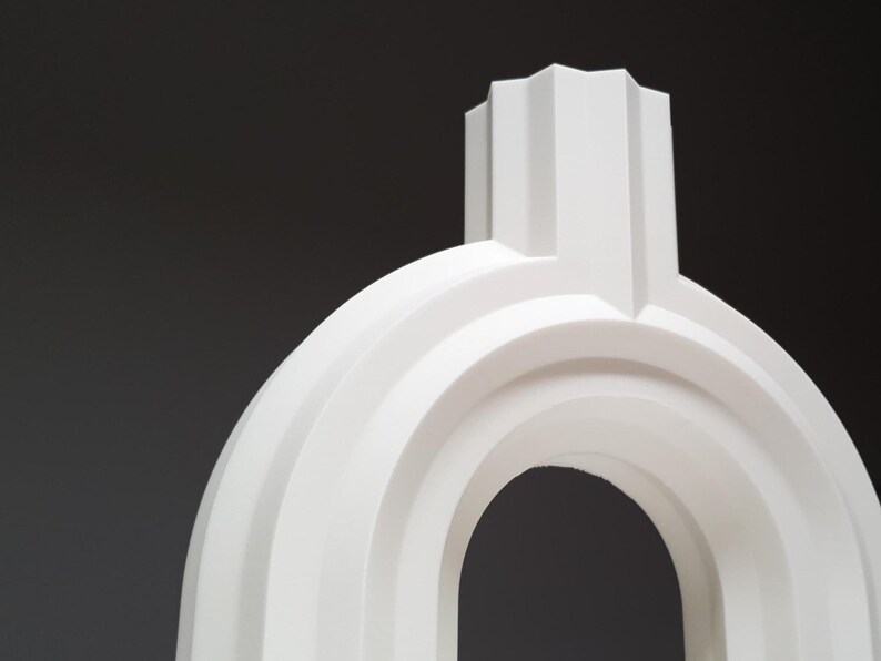 A close-up view of the top section and arch of the white ribbed geometric vase.