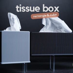 Könnte beinhalten: Eine würfelförmige weiße Taschentuchbox und eine rechteckige schwarze Taschentuchbox, beide mit vertikal gerippten Texturen und durchsichtigen Acrylständern. Der Text tissue box und rectangle & cube ist über den Objekten zu sehen.