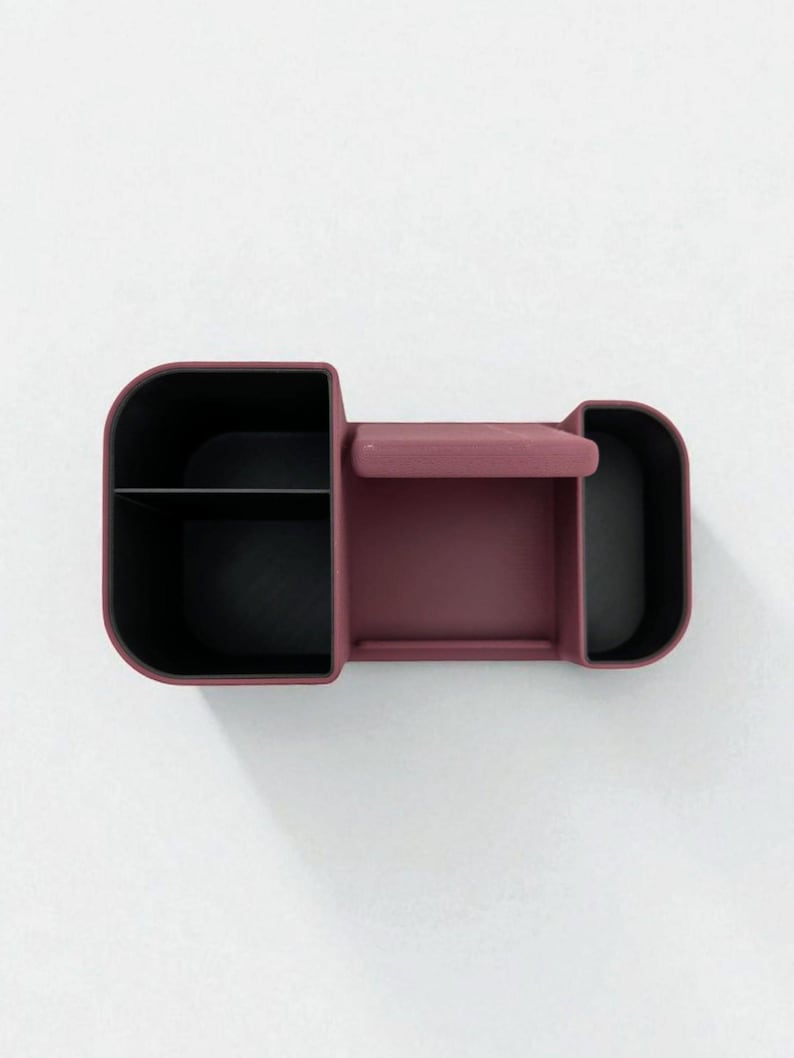 An overhead shot of a dark pink desk organizer with black compartments, showing its three sections and phone stand.