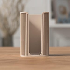 May include: A beige, rectangular holder with vertical ribbed detailing on the sides. The open-faced design allows for easy access to the contents. The holder is made of a solid material and sits on a wooden surface.