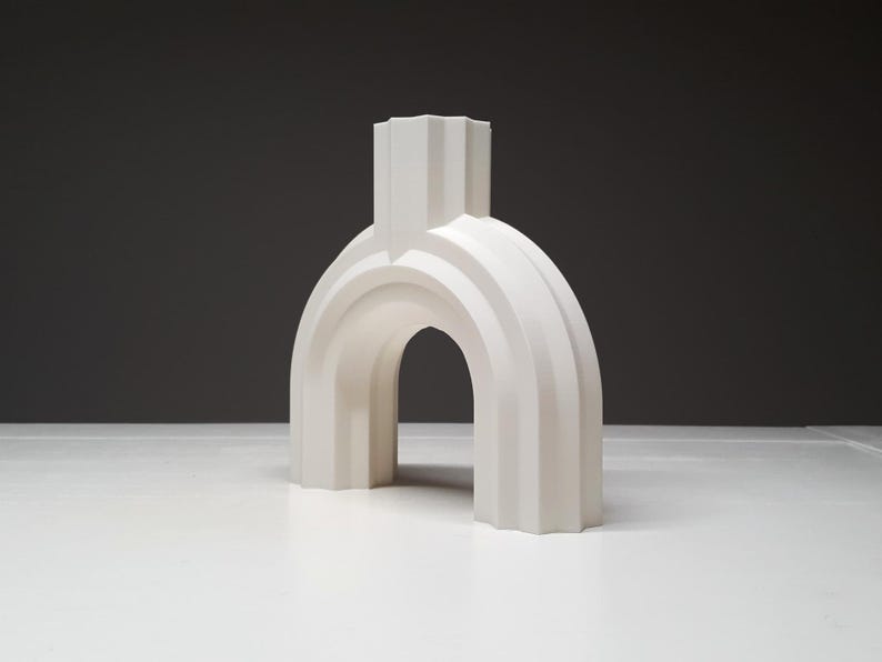 A three-quarter angle view of the white arched ribbed vase on a white table against a dark grey backdrop.
