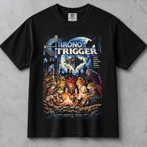 May include: A black short-sleeved t-shirt featuring a graphic print of the Chrono Trigger video game characters sitting around a campfire. The design includes the text Chrono Trigger, Good People Bad Times Great Stories, and Some Journeys Never End.