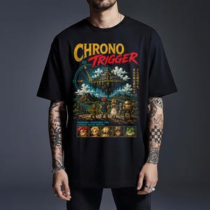 May include: A black short-sleeved t-shirt featuring a large Chrono Trigger graphic print. The design includes a floating castle, a group of characters, a clock face, Japanese text, and the English text "FRIENDSHIP TRANSCENDS TIME. COURAGE DEFIES DESTINY."