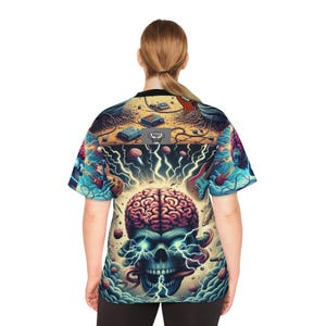 May include: A short-sleeved shirt with a vibrant, surreal design featuring a brain, skull, lightning bolts, and musical instruments. The artwork includes a variety of colors, including blue, red, and yellow, creating a psychedelic effect. The shirt has a black collar.