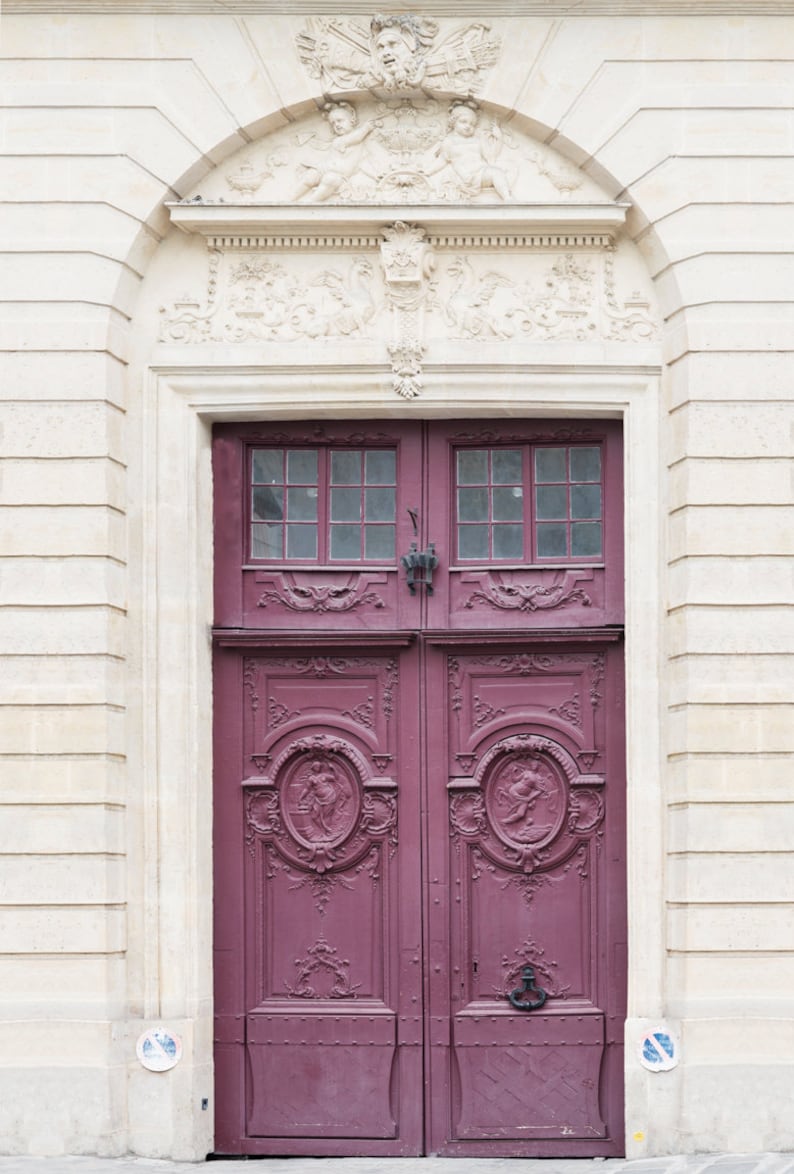 May include: A pair of ornate, double doors with intricate carvings and a deep purple paint finish. The doors are set within a white stone archway with decorative carvings.