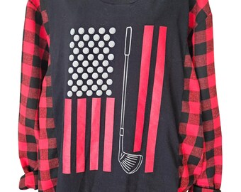 Puede incluir: Una camiseta de manga larga con torso negro y mangas de cuadros rojos y negros. El frente presenta un diseño gráfico de una bandera estadounidense donde las estrellas son reemplazadas por pelotas de golf blancas y un palo de golf.