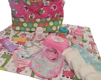 Puede incluir: Un bolso de bebé rosa y verde con lunares y varios artículos para el cuidado del bebé. Incluye un cambiador, pañales, biberones, toallitas, babero, chupete y loción. El cambiador tiene un estampado de jirafas.