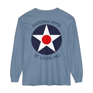 May include: A light blue long-sleeved t-shirt with a navy blue circle and white star with a red center. The text "GATEWAY IPMS ST. LOUIS, MO" is printed on the shirt.