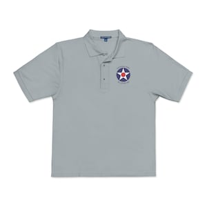 May include: A light gray polo shirt with short sleeves. The shirt has a collared neckline and a three-button placket. A circular emblem with a red star and the text "Gateway PMS St. Louis, MO" is on the left chest.