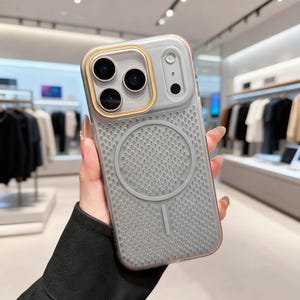 Op de afbeelding: Een doorzichtige en grijze telefoonhoes met een getextureerde achterkant en een goudkleurig camerakader. De hoes heeft een cirkelvormig ontwerp op de achterkant en is ontworpen om de cameralenzen van de telefoon te beschermen.