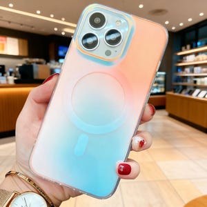 Puede incluir: Una funda transparente para teléfono con un diseño degradado, que transiciona de melocotón a azul. La funda tiene un diseño circular en la parte posterior y un borde transparente. La funda está diseñada para un teléfono inteligente.