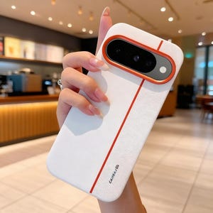 Può includere: Custodia per telefono bianca con una striscia e dettagli rossi. La custodia ha un ritaglio per la fotocamera con un bordo arancione. La parola "CAMERA" è stampata in basso a destra.