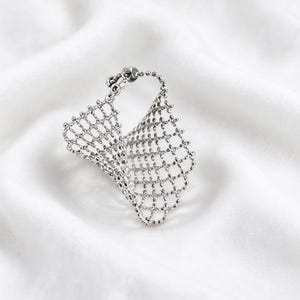 May include: A silver-toned ring featuring a flexible, open-work mesh design. The band is constructed from a delicate, interconnected grid of small metallic beads, creating a lightweight, textured, and dimensional appearance.