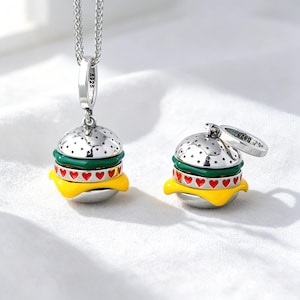 May include: A silver hamburger charm pendant on a chain and a matching silver hamburger charm, both featuring a silver bun with dots, a green lettuce layer, a red tomato layer with small red hearts, and a yellow cheese layer, marked S925.