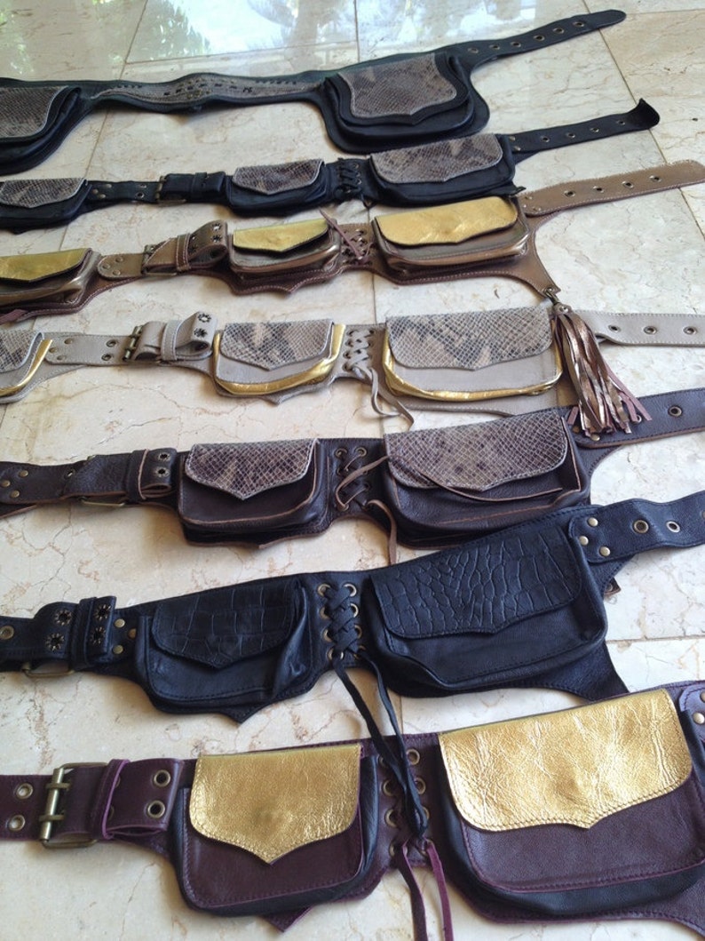 Pu&ograve; includere: Una collezione di marsupi in pelle in vari colori e texture. Alcuni presentano stampa di serpente, dettagli dorati e frange. Le cinture hanno cinghie regolabili e pi&ugrave; tasche. I colori includono nero, marrone e beige.