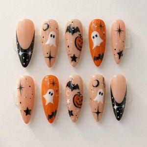 以下が含まれることがあります： ハロウィンをテーマにしたアーモンド型のプレスオンネイル10本セット。黒いフレンチチップに白い星、オレンジの背景に白いお化け、黒いコウモリ、オレンジのカボチャ、黒い星、三日月などがヌードカラーのベースに描かれています。