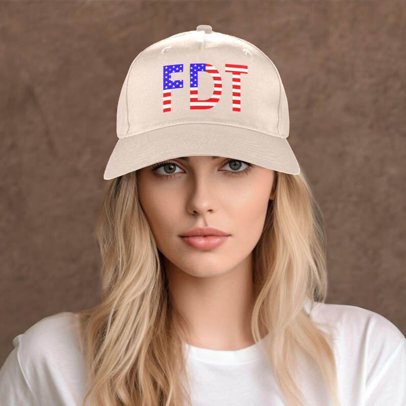 May include: A cream-colored baseball cap with the letters "FDT" in red and blue, designed to resemble the American flag. The hat has a curved brim and a classic six-panel design.