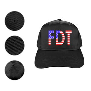 May include: Black baseball cap with the letters "FDT" in a design that resembles the American flag. The cap has a curved brim and a button on top. The image also shows close-ups of the cap's fabric and construction details.